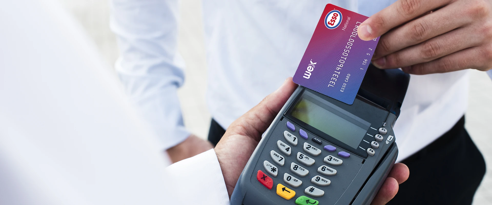 A person holding an Esso Fuel Card against a contactless card machine